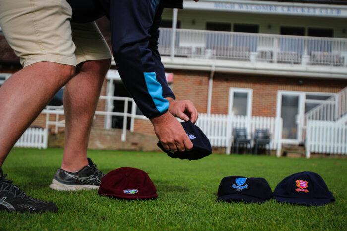 Chris Sketchley setting down four baggy cricket caps on the ground: West Indies, Yorkshire, Sussex and Essex baggy caps.